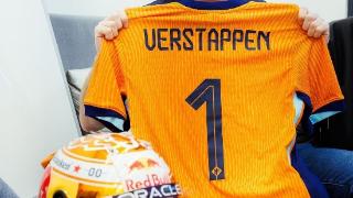 F1车手维斯塔潘手持定制的荷兰1号球衣，为荷兰加油助威